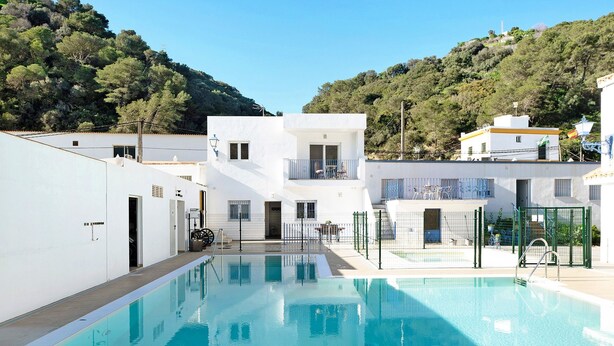 Ein Swimmingpool mit Blick auf eine Hügelsicht, weiße Gebäude und einen klaren Himmel.
