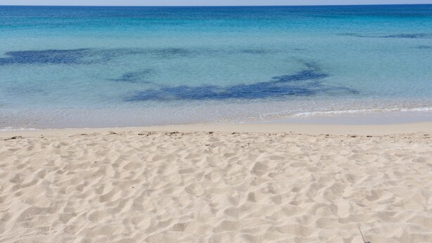 Een strand met helder water en zand.