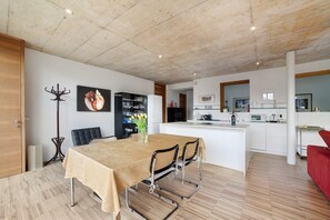 Een moderne keuken met witte kastjes, een centraal eiland en een eethoek met tafel en stoelen.