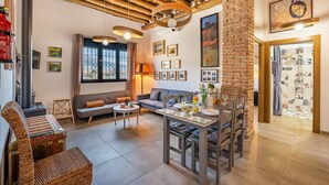 A living room with a sofa, dining table, and chairs, a fireplace, and a large window. - Country House 'La Criba - Casa Rural Eralta' with Mountain View, Wi-Fi and Air Conditioning (Dúrcal)