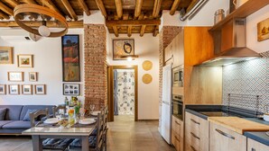 A modern kitchen with wooden cabinets, a stainless steel range hood, and a dining area with a table set for two. - Country House 'La Criba - Casa Rural Eralta' with Mountain View, Wi-Fi and Air Conditioning (Dúrcal)