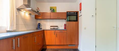 A compact kitchen with wooden cabinets, a built-in oven, and a coffee maker.
