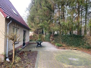 A paved pathway leading to a building with a red roof, surrounded by trees and greenery. - Free Holiday Home With big Garden (Schoonloo)