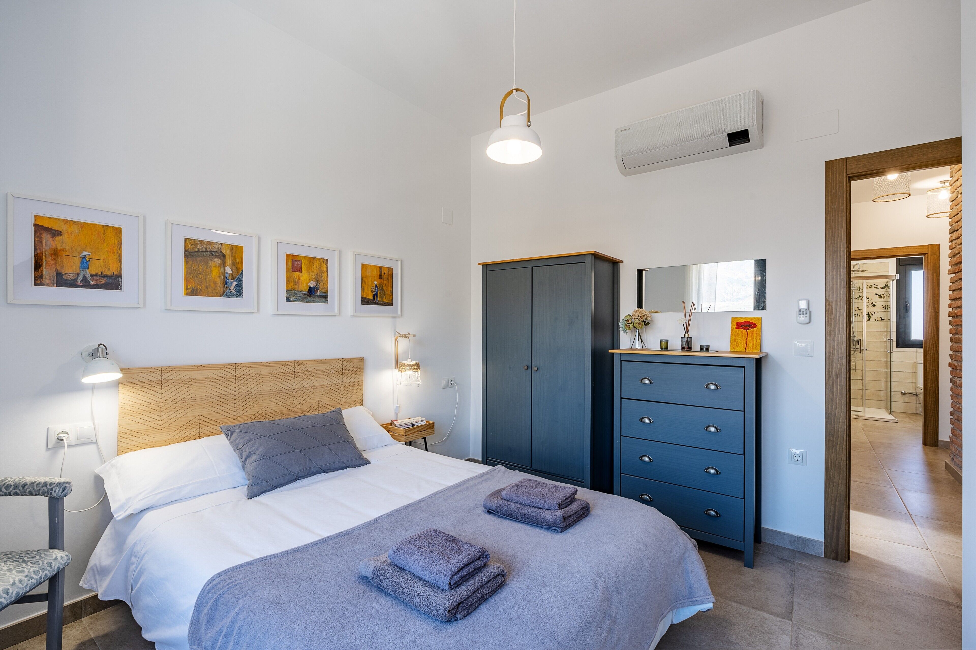 Una camera da letto con un letto, comodini, un armadio e opere d'arte alle pareti.