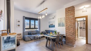 Un salon moderne comprenant un coin repas, une grande fenêtre offrant une belle vue, un mur décoratif en briques et un espace douche.