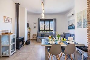 A modern living room with a dining area, a fireplace, and a large window with a view.