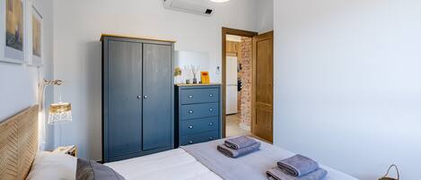 A bedroom with a bed, a wardrobe, a hanging lamp, and a door leading to a bathroom.