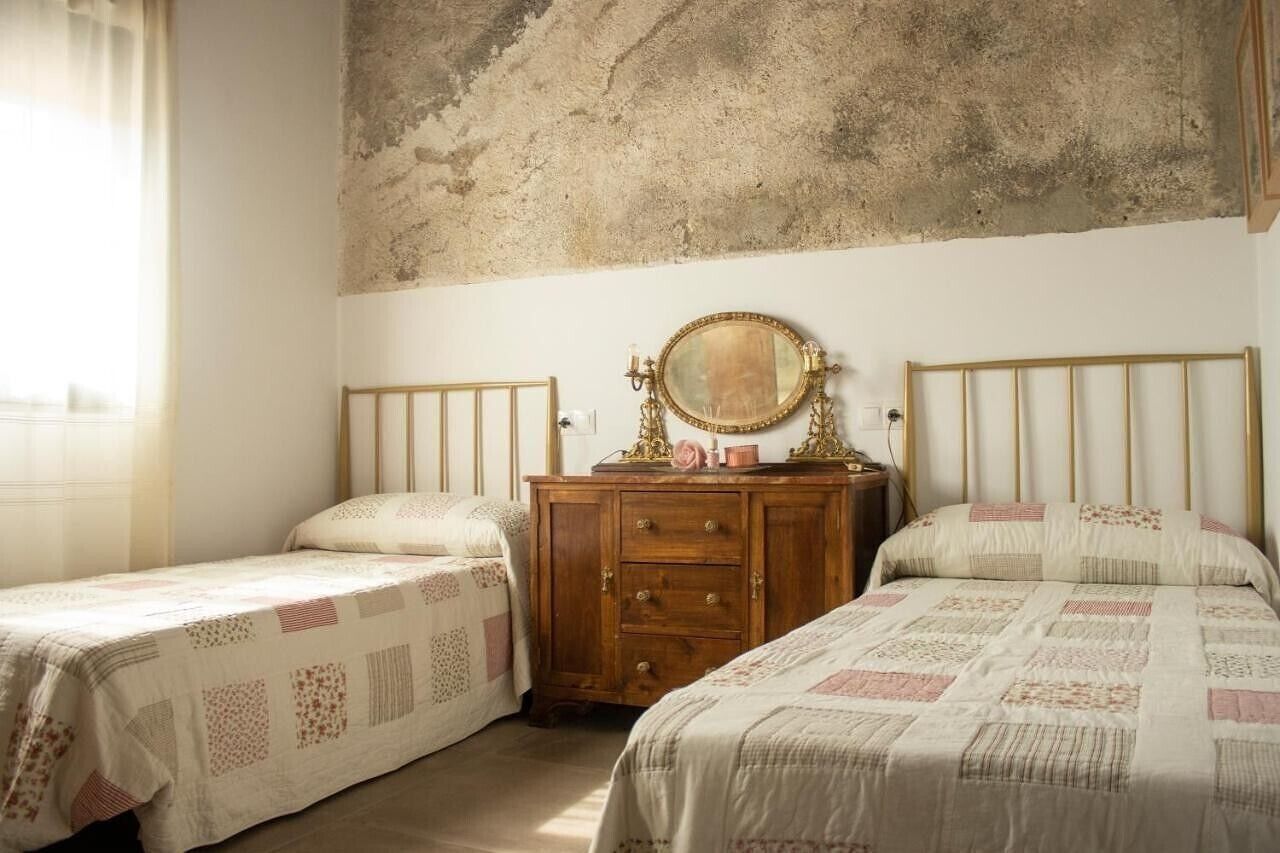 Een slaapkamer met twee eenpersoonsbedden, een houten dressoir en een grote spiegel.