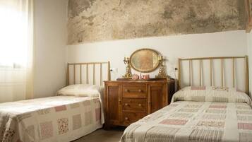 Een slaapkamer met twee eenpersoonsbedden, een houten dressoir en een grote spiegel.