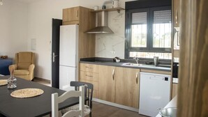 A modern kitchen with wooden cabinets, a black countertop, a built-in oven, and a window with blinds. - Country House "Eralta" with Mountain View, Private Pool & Wi-Fi (Dúrcal)