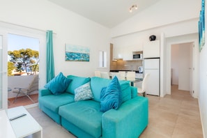 Un salon moderne avec un canapé de couleur turquoise, un coin repas et une cuisine.