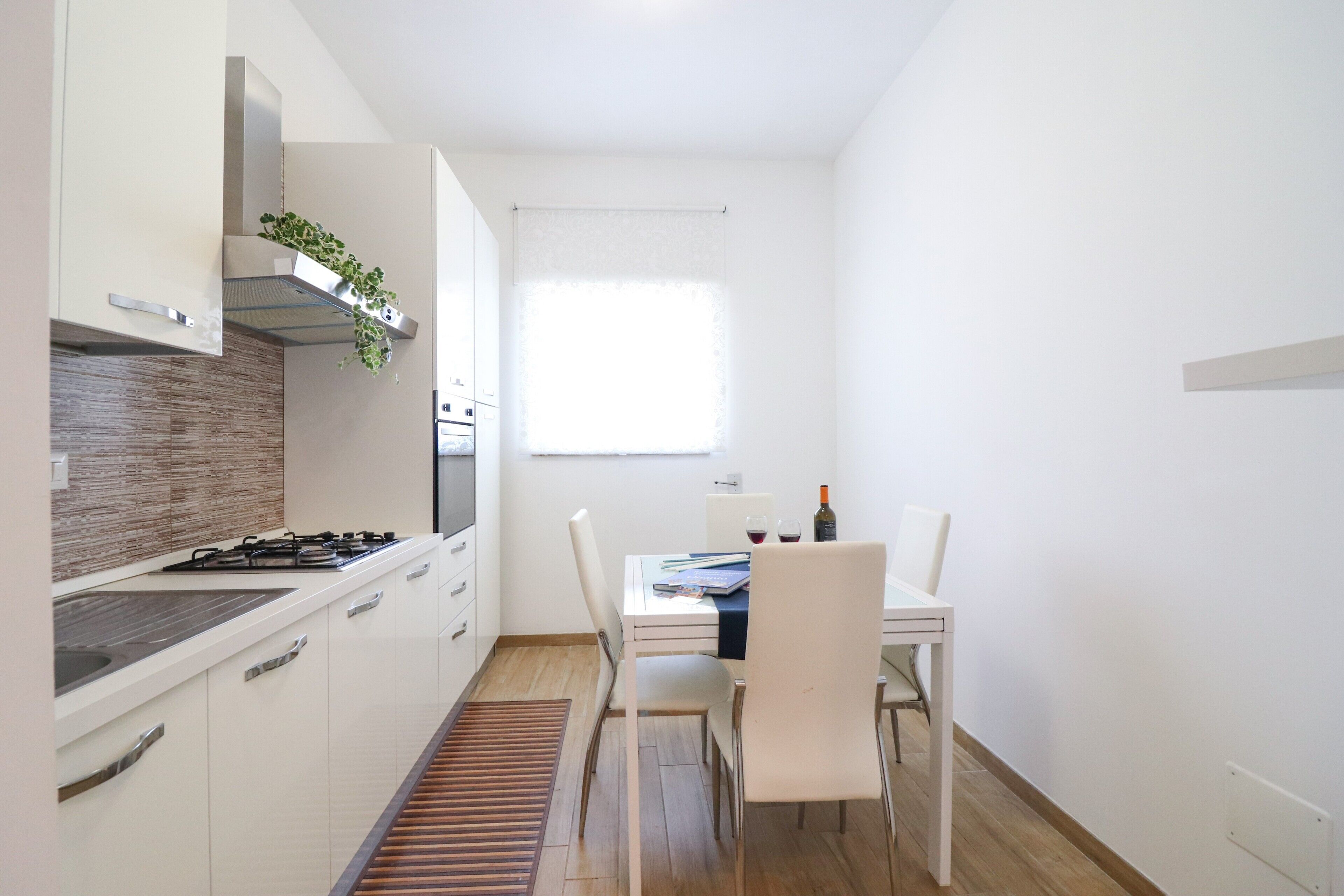 Una cocina moderna con armarios blancos, estufa a gas y una ventana con persianas.