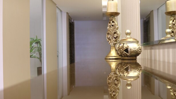 A polished hallway with a reflective floor, a decorative golden lamp, and a potted plant. - Tri Hotel Xanxerê (Xanxere)
