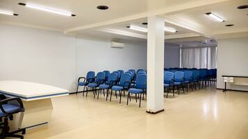 A conference room with rows of blue chairs, a white table, and recessed ceiling lighting.
