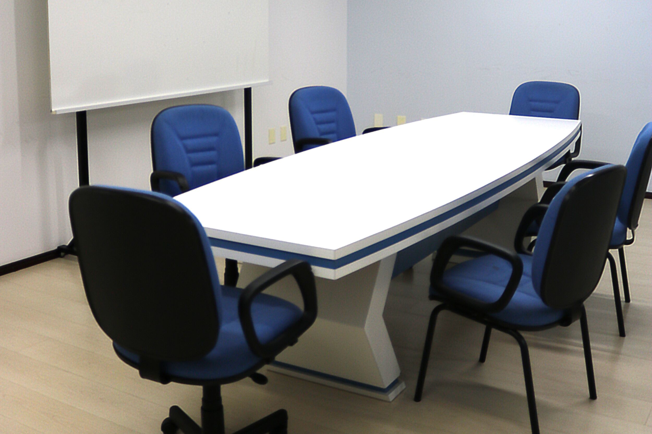 A conference room with a long table and six blue chairs.