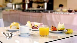 A breakfast table with plates of food, a glass of orange juice, and a banana. - Tri Hotel Xanxerê (Xanxere)