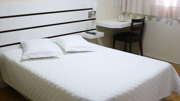 Una cama bien hecha con ropa de cama blanca y un cabecero con rayas horizontales negras.