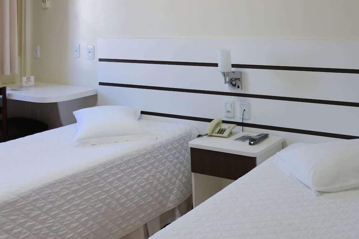 Ein Hotelzimmer mit zwei Betten, einem Nachttisch mit Telefon und einer Wandleuchte.