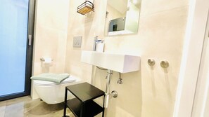 A bathroom with a toilet, sink, and mirror. - Townhouse Bombarda (Lagos)
