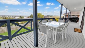 Eine überdachte Terrasse im Freien mit Tisch und Stühlen, einem Grill und Blick auf die umliegende Landschaft.