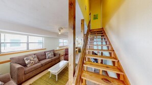 A living room with a sofa, coffee table, and a wooden staircase.