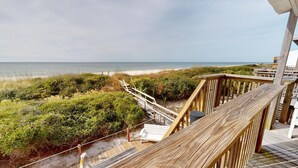 A wooden deck with a view of the beach and ocean.