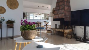 Una sala de estar moderna con chimenea, muebles blancos y plantas decorativas.