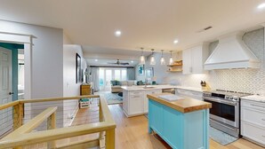 Een moderne keuken met witte kastjes, een blauw eiland en roestvrijstalen apparatuur.
