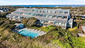Een hotel aan het strand met meerdere verdiepingen, een zwembad, balkons en uitzicht op de oceaan.