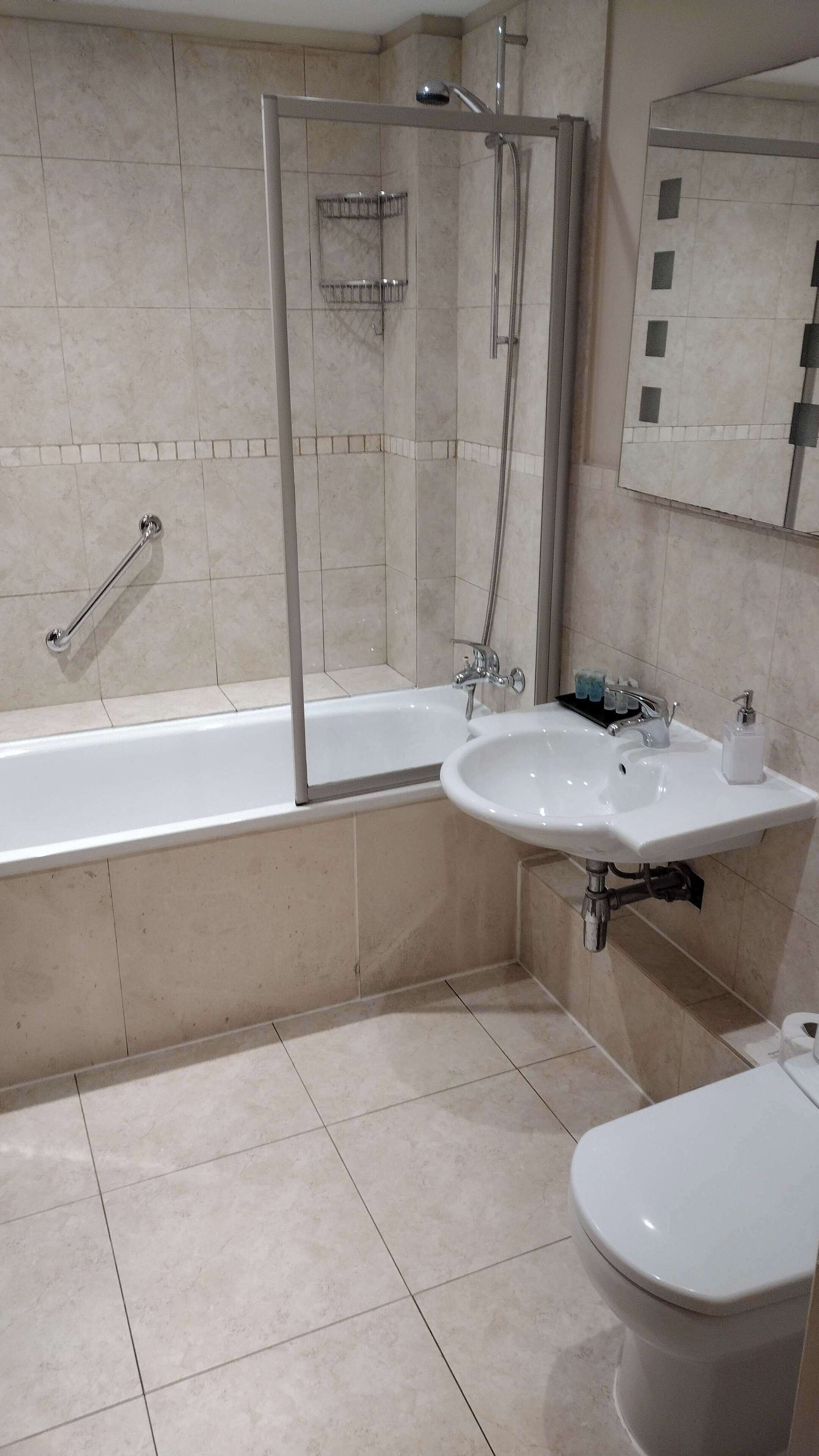 A modern bathroom with a glass-enclosed shower, a white bathtub, a sink, and a toilet.