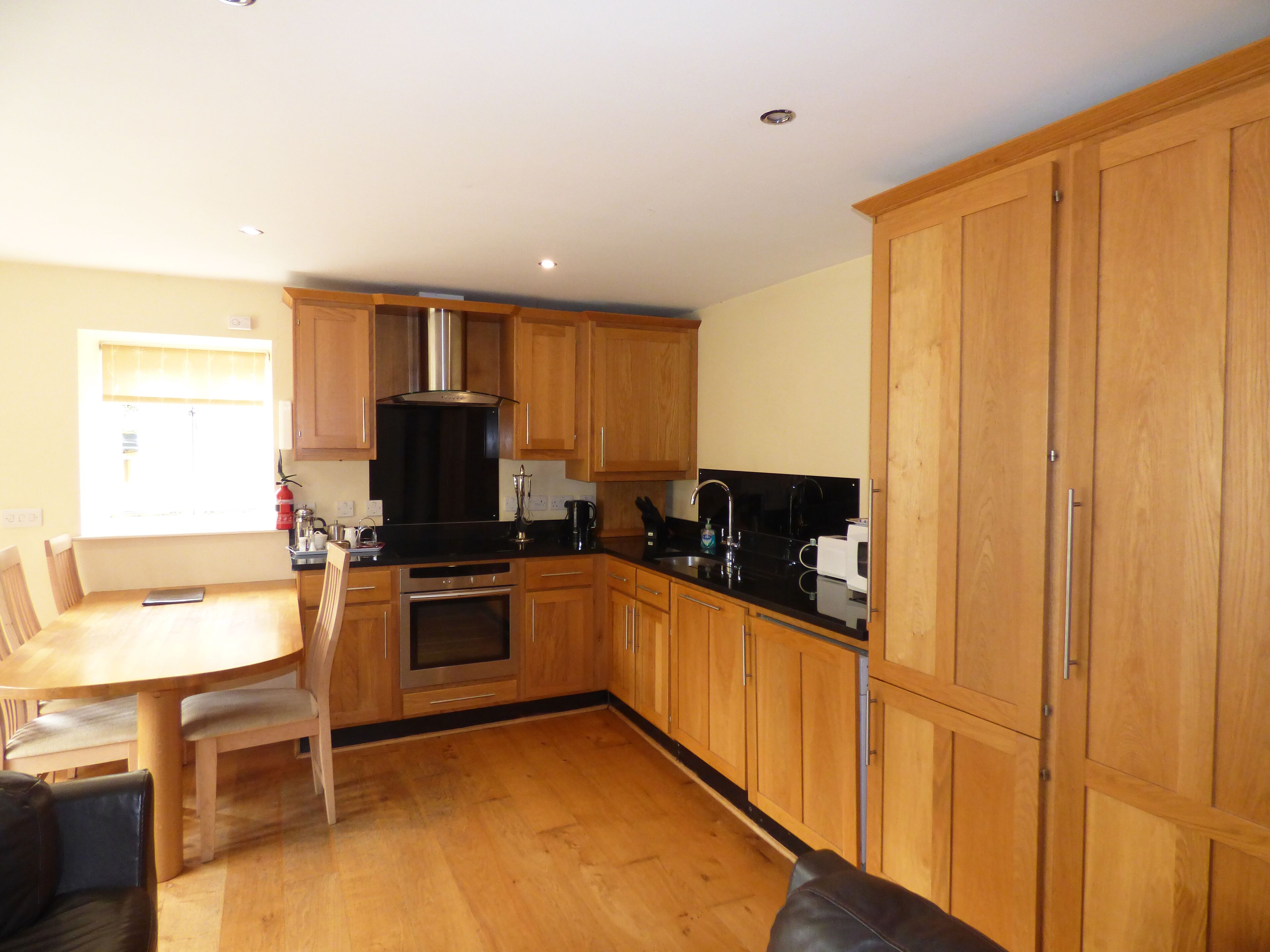 A kitchen with wooden cabinets, a black countertop, and a dining area with a table and chairs.