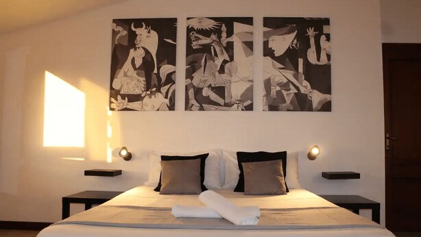 A hotel room with a large bed, two bedside tables, and three abstract paintings on the wall. - Comfortable apartment in nature (FREE PARKING)-just a stone's throw from the park (Castel di Leva)