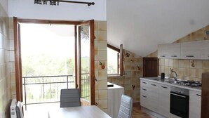 A kitchen with a dining area, a view through the open door, and a balcony. - Comfortable apartment in nature (FREE PARKING)-just a stone's throw from the park (Castel di Leva)