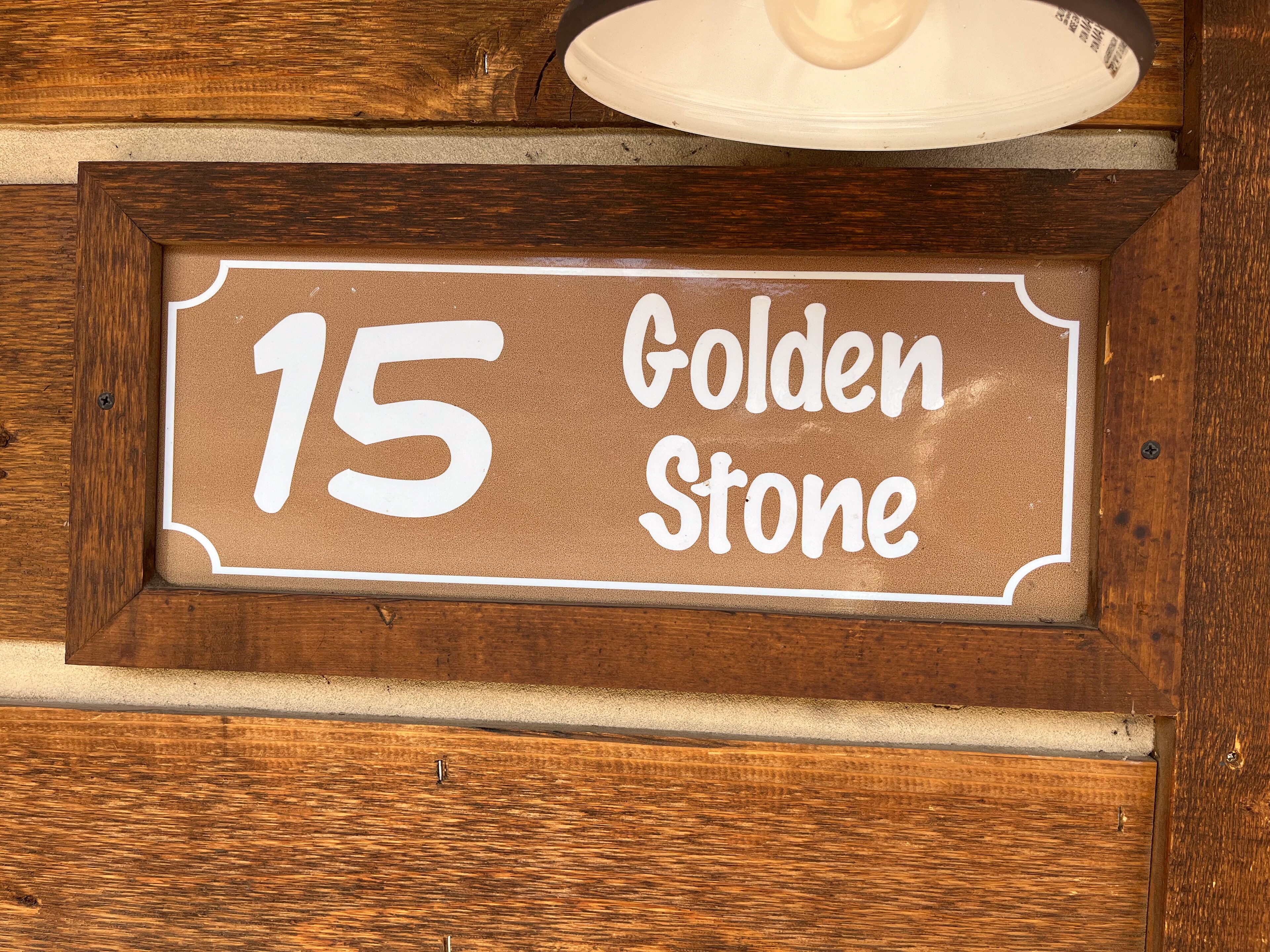 A wooden sign with the number 15 and the words "Golden Stone" on it.