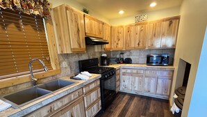 A kitchen with wooden cabinets, a stainless steel sink, a stove, and a microwave. - Fabulous 5 BR Vacation Home on the Taylor River (Almont)