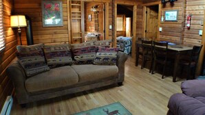 A cozy log cabin interior with a sofa, a dining table, and chairs.