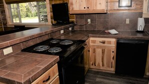 A kitchen with wooden cabinets, a stove, and a dishwasher. - Roomy Taylor Canyon Cabin With Private Fishing Access (Almont)