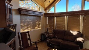 Ein gemütliches Wohnzimmer mit Kamin, einer Couch, einem Esstisch und einem Sessel.