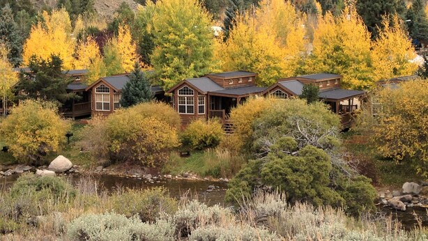 A row of log cabins with a river in the foreground and a forested hillside in the background. - Modern "Tiny Home" Style Cabin on Taylor River with Private Fishing Access (Almont)