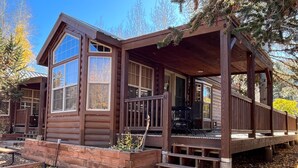 A log cabin with a porch, large windows, and a staircase leading to the entrance. - Modern "Tiny Home" Style Cabin on Taylor River with Private Fishing Access (Almont)
