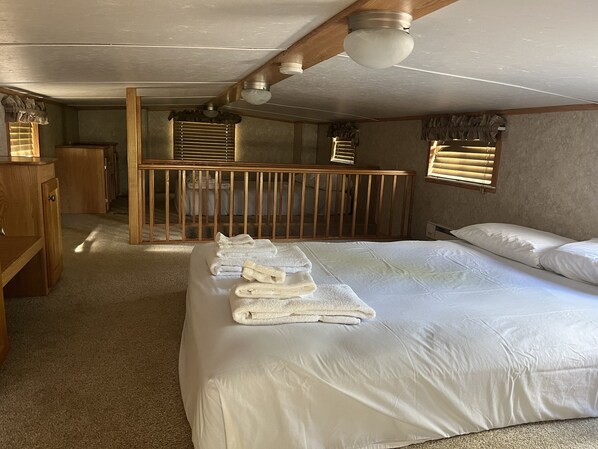 Une chambre à coucher avec un grand lit, un berceau en bois, un bureau et une fenêtre avec des stores.