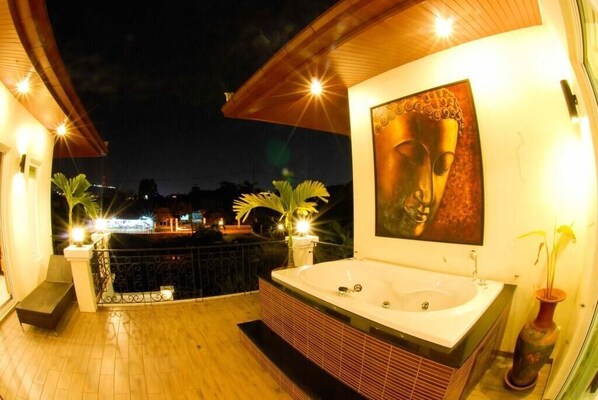 Un balcon bien éclairé, doté d’une grande baignoire, d’une statue de Bouddha et d’une plante en pot.