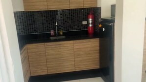 A kitchen with black countertops, wooden cabinets, and a red fire extinguisher. - Most beautiful Penthouse! (Muang Pattaya)