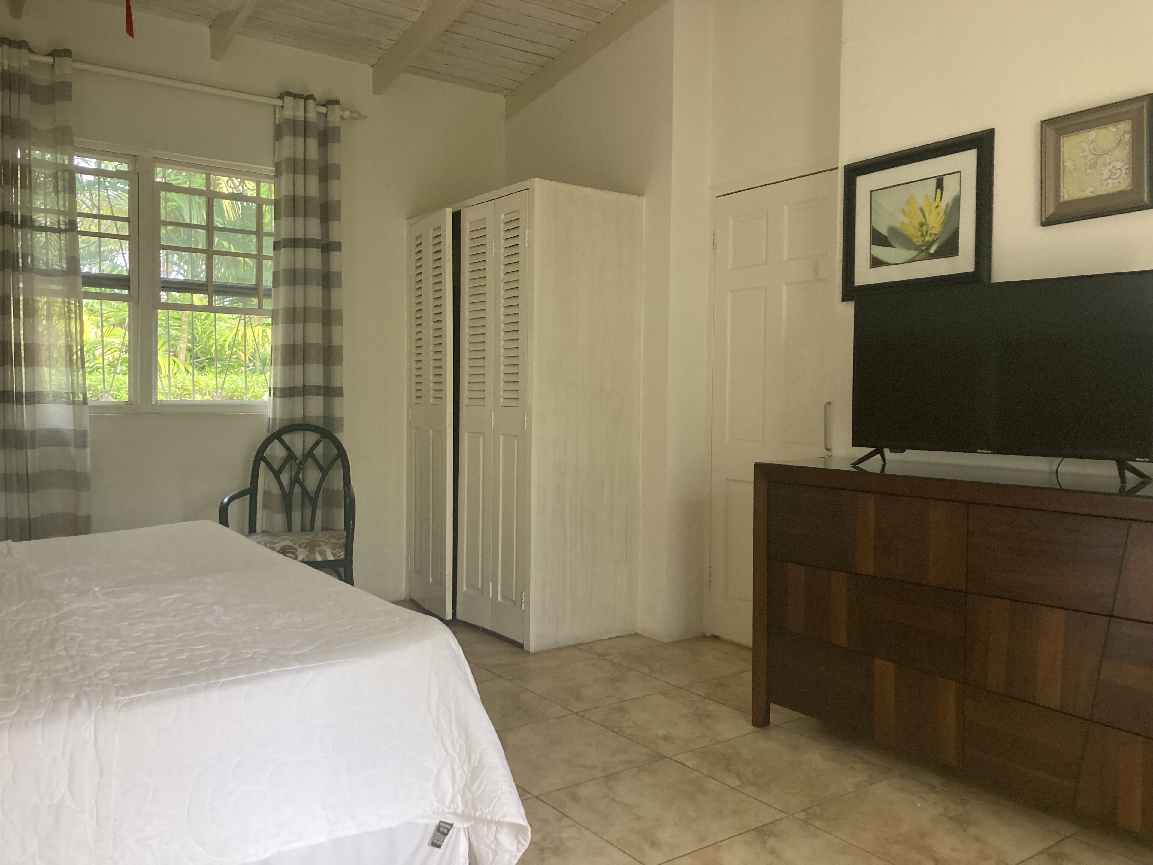 Una camera da letto con un letto, una sedia, un armadio, una cassettiera e un televisore.