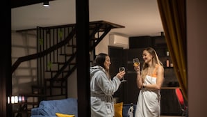 Una sala de estar moderna con un sofá azul, una escalera de madera y un separador de vidrio.