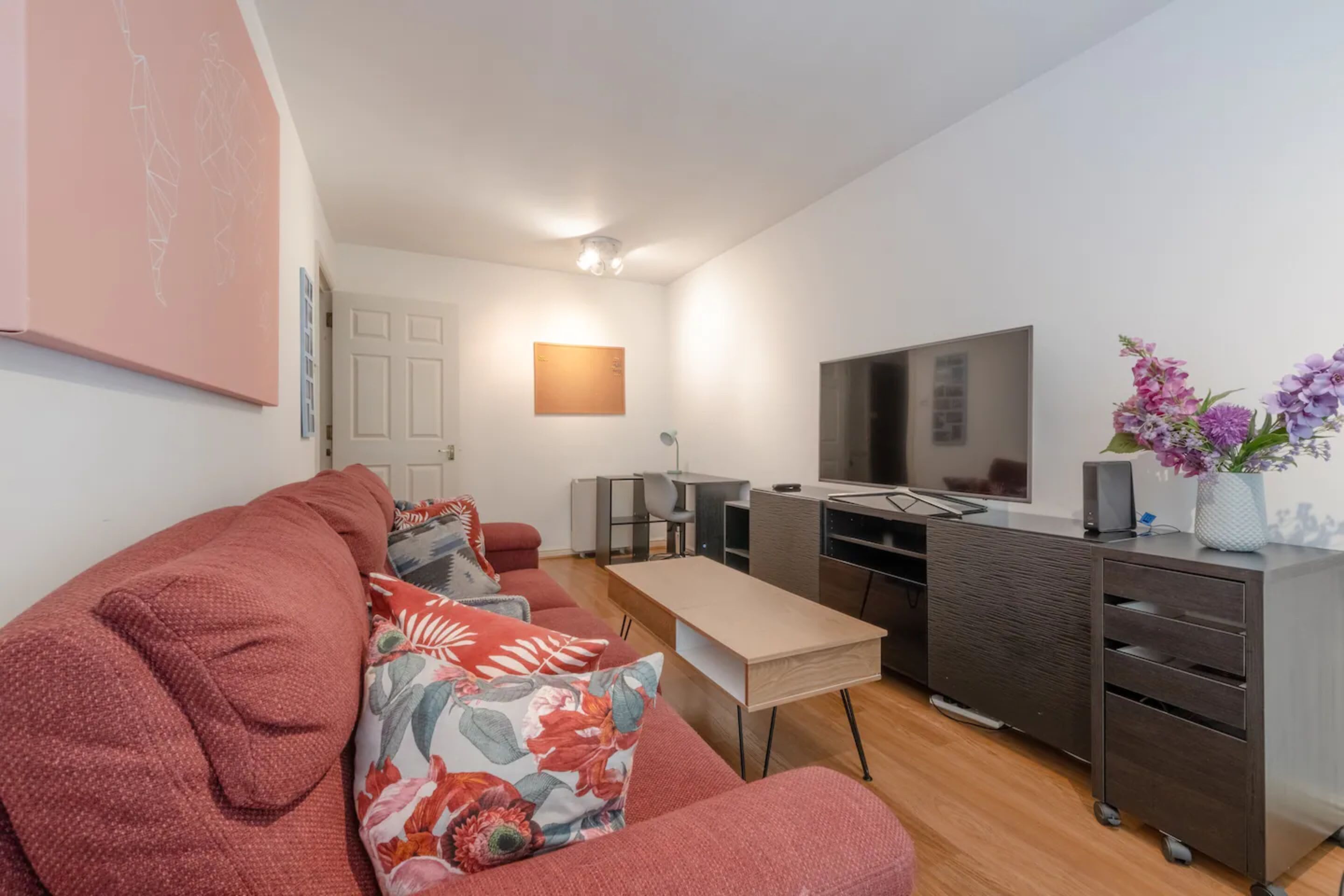 A modern living room with a sofa, a coffee table, a TV, and a desk.