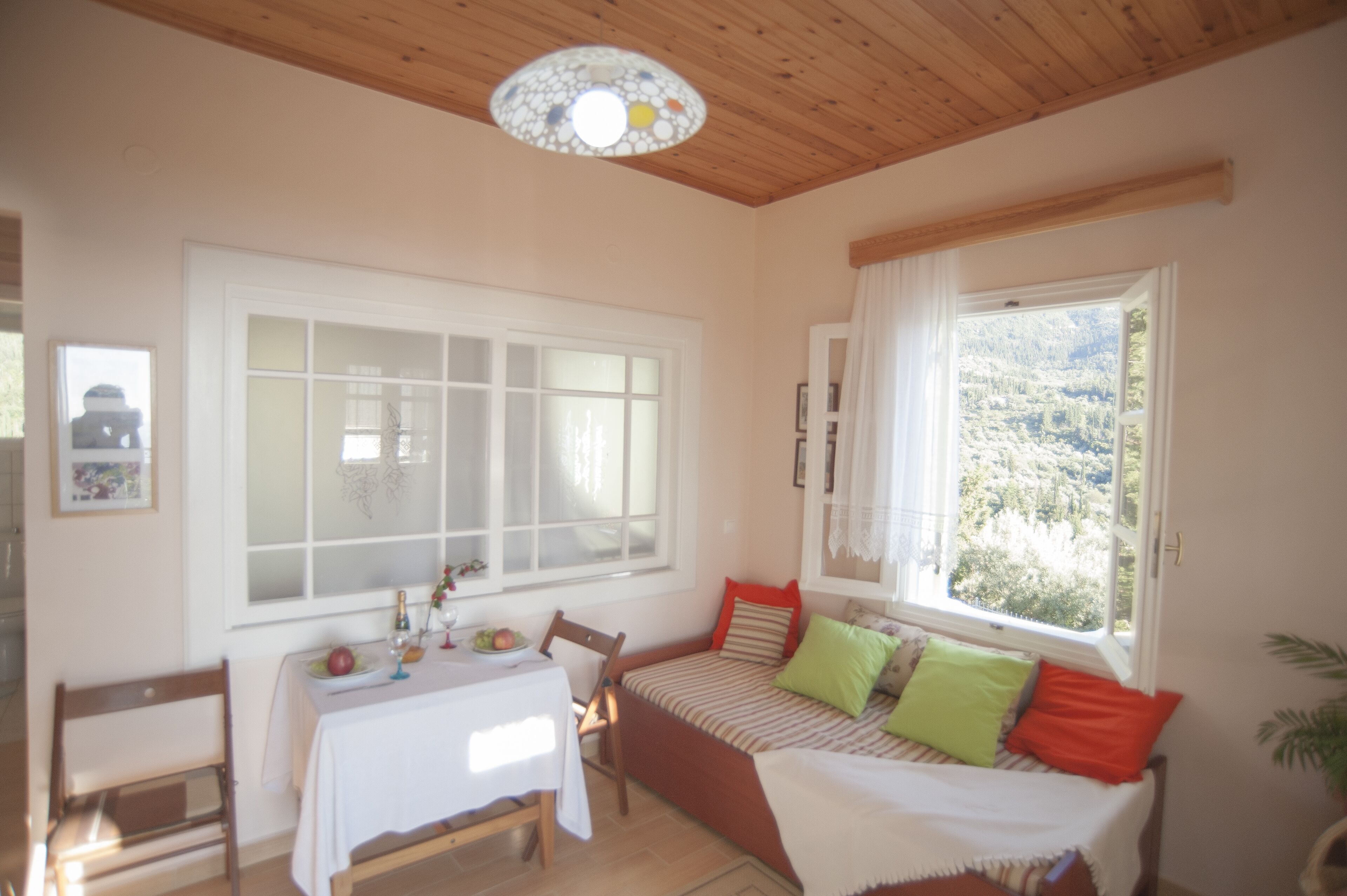 A cozy room with a bed, a dining table, and a large window with a view of a mountainous landscape.