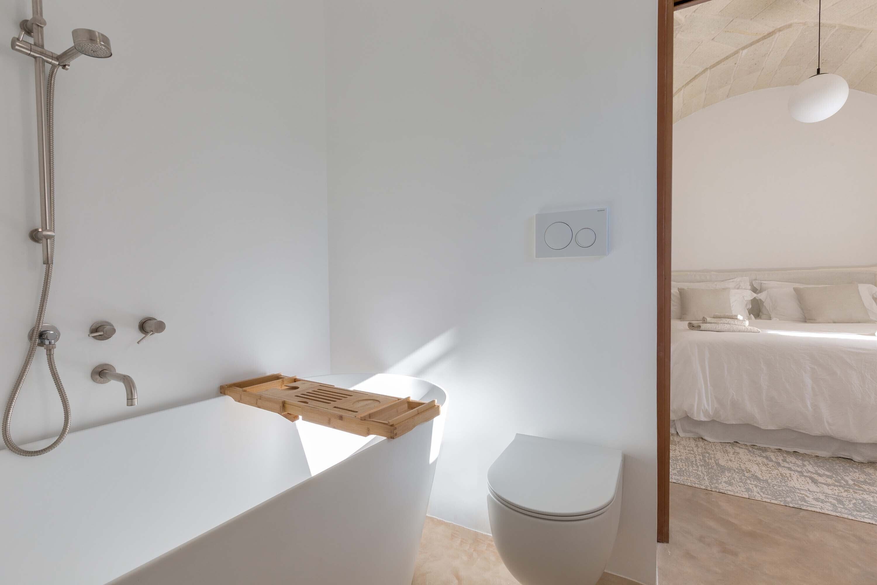 Ein modernes Badezimmer mit einer freistehenden Badewanne, einer Toilette und einer Duschbrause.