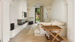 Un salon moderne avec un canapé blanc, une table basse en bois et un téléviseur fixé au mur.