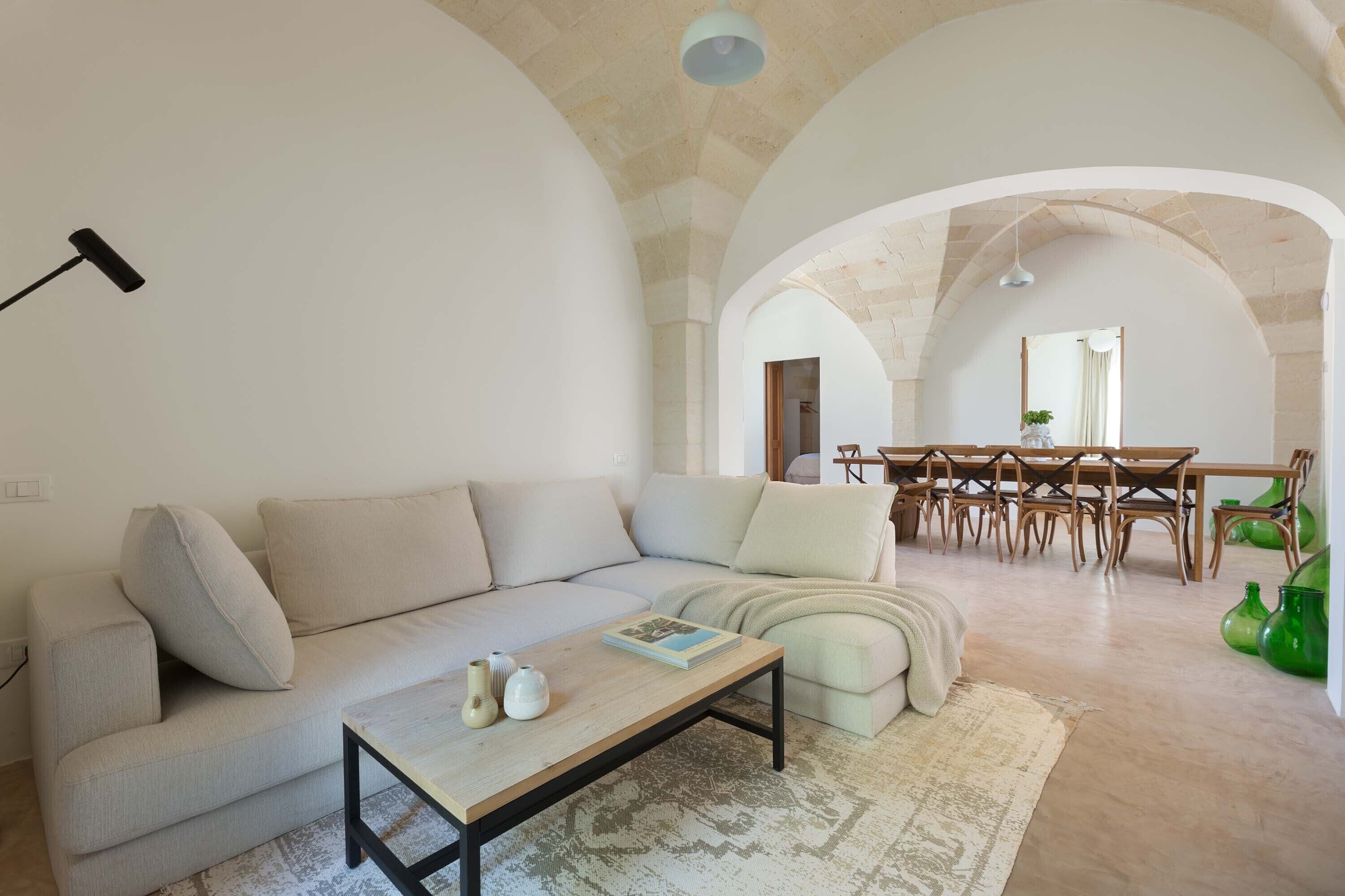 A spacious living area with a sofa, a coffee table, and a dining table with chairs.